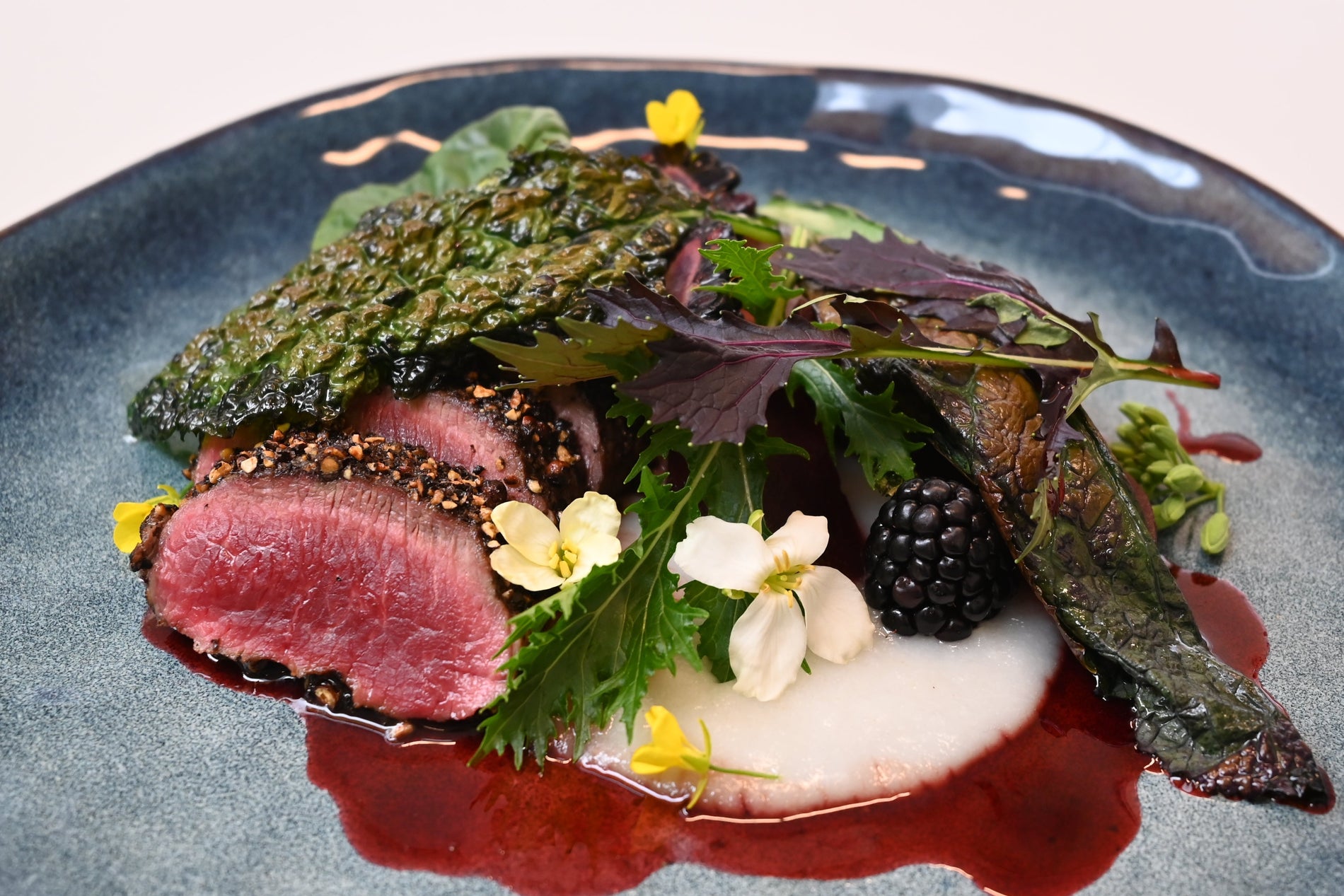 Pepper Crusted Venison Backstrap, with soft white polenta, pickled plum, wilted greens and roasted blackberries